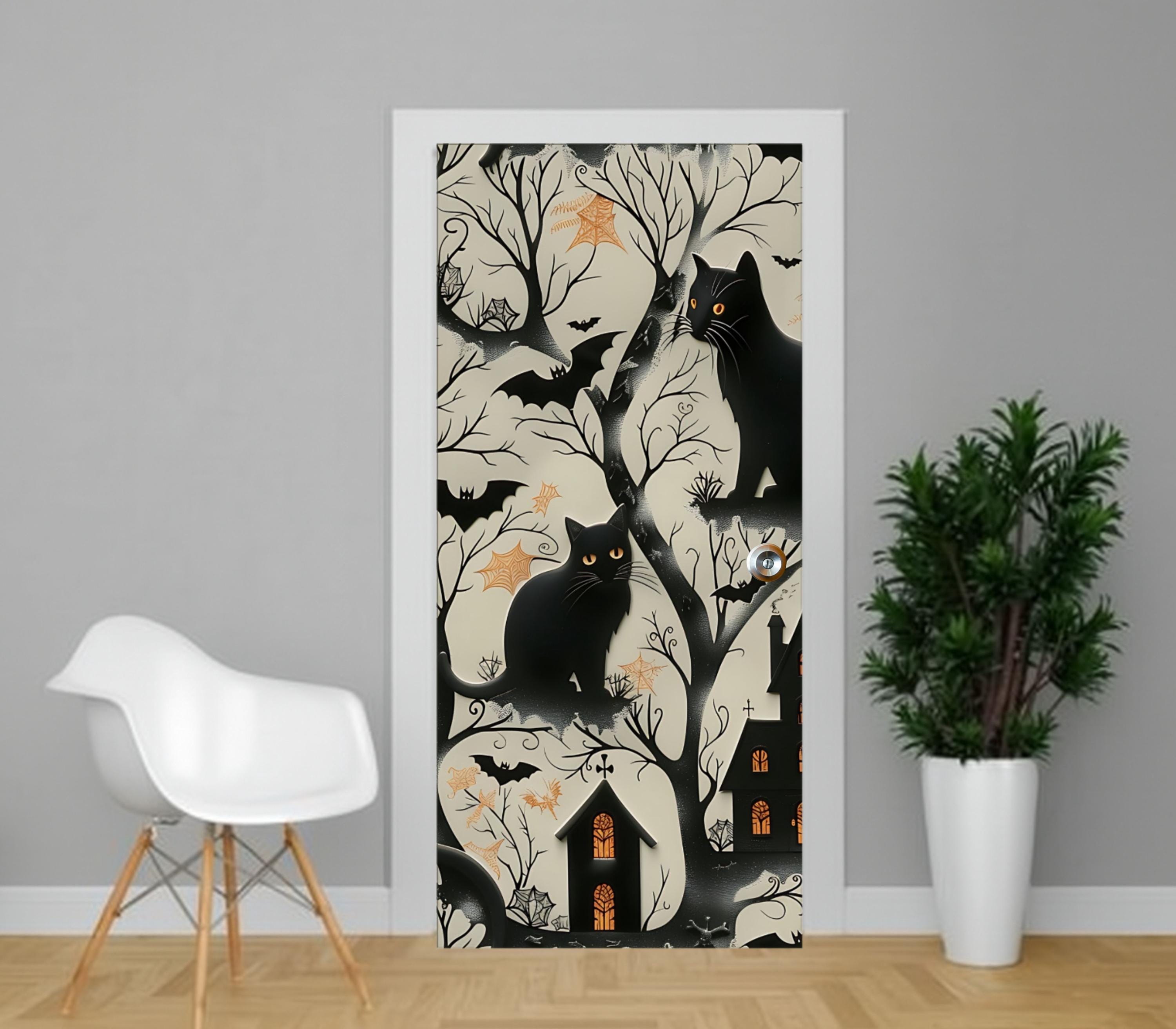 a door with a Halloween-themed design, including black cats, bats, and a house with a chimney. There is a white chair and a potted plant in the foreground, and the door is set in a gray wall.